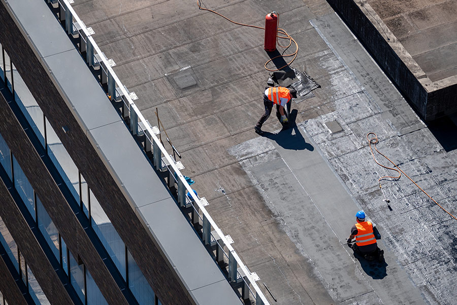 aerial view of contractors applying insulation system at commercial building roof